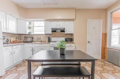 a kitchen with white cabinets and a table with a potted plant at NYC Train EWR Liberty Park 1 in Bayonne
