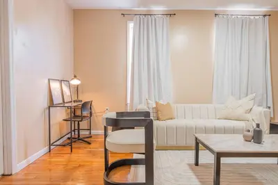 a living room with a white couch and a table at Private BR Wlk to NYC Train 3 in Bayonne