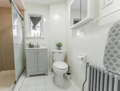 a white bathroom with a toilet and a sink at NYC Train EWR Liberty Park 2 in Bayonne