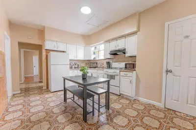 a kitchen with a table and a white refrigerator at NYC Train EWR Liberty Park 2 in Bayonne