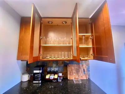 a kitchen with wooden cabinets with glasses on shelves at Easy PATH&Bus access- NYC designer home & Terrace in Jersey City