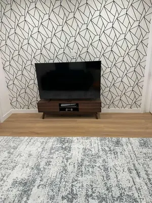 a flat screen tv in a living room with a geometric wallpaper at The View - Direct Bus Time Square NYC Breakfast Included - D in Jersey City