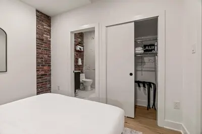a bedroom with a white bed and a brick wall at Sleep 3- Beautiful Unit- Walk Around in Old City in Philadelphia