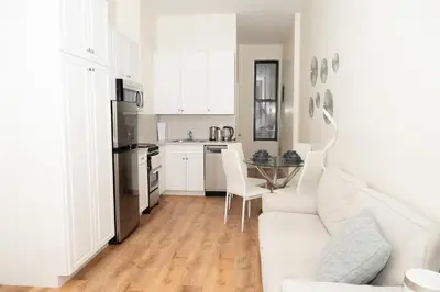 a white living room with a white couch and a kitchen at East Village Center Apartment7 w Full Amenities Great New York Location in New York