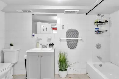 a white bathroom with a tub and a toilet and a sink at Cozy Private Apartment Near NYC Light Rail in Bayonne
