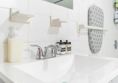 a white bathroom with a sink and a mirror at Cozy Private Apartment Near NYC Light Rail in Bayonne