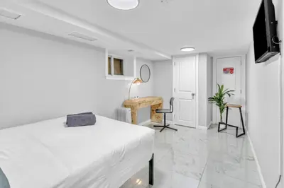 a white bedroom with a bed and a desk at Cozy Private Apartment Near NYC Light Rail in Bayonne