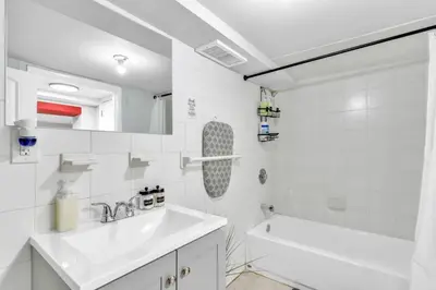 a bathroom with a sink and a tub and a toilet at Cozy Private Room in Shared Space NYC Light Rail BSMT A in Bayonne