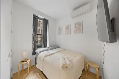 a white bedroom with a bed and a tv at Double Room at a shared Apartment near Times Square in New York
