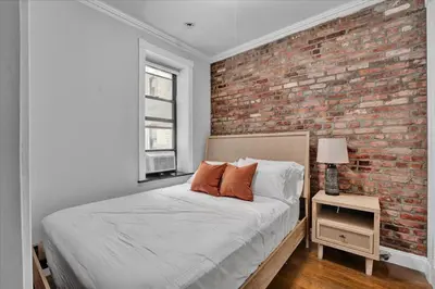 a bedroom with a brick wall and a bed at Stylish 3BR-2BA in Gramercy in New York