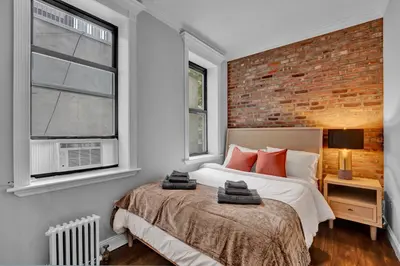 a bedroom with a bed and a brick wall at Elegant 3BR-2BA in Gramercy -Modern & Central in New York