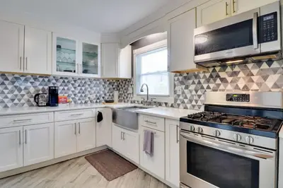 a kitchen with white cabinets and stainless steel appliances at The Vault Your Fun Secured in Hillside