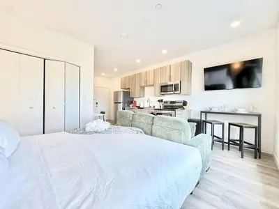 a bedroom with a large white bed and a kitchen at Boutique Studio with Rooftop View and Gym in Philadelphia