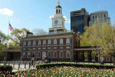a building with a clock tower on top of it with flowers at Studio Apt Near Temple Unit with Free Parking for Extended Stays in Philadelphia