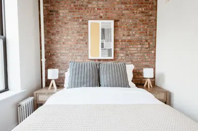 a bedroom with a brick wall and a bed at Spacious 3BR Upper West Side Apt - Steps from Central Park in New York