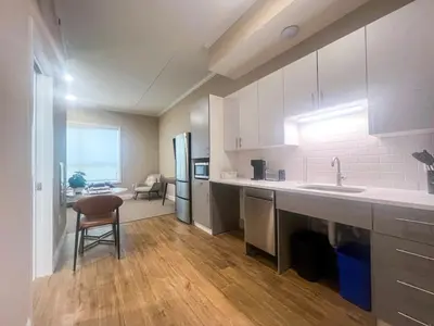 a kitchen with white cabinets and a table and a chair at 415 Modern Brand New Studio Apartment in Old Bridge