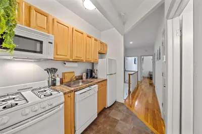 a kitchen with white appliances and wooden cabinets at The Global Nook - Private Room with Shared Bathroom near Times Square in New York