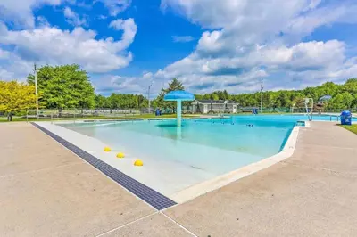a large swimming pool with a blue umbrella at Lake Access, Hot Tub, Fire Pit in Arrowhead Lake