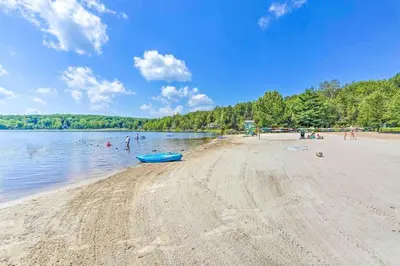 a beach with a blue boat in the water at Lake Access, Hot Tub, Fire Pit in Arrowhead Lake