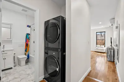 a black washer and dryer in a white bathroom at Carroll Place - Bright 3BR Apt in Carroll Gardens in Brooklyn