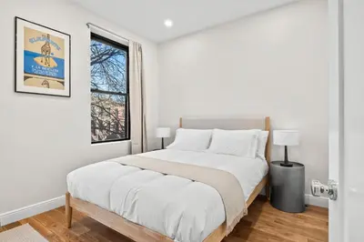 a white bedroom with a large bed and a window at Carroll Place - Bright 3BR Apt in Carroll Gardens in Brooklyn