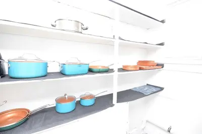 a row of pots and pans on shelves in a kitchen at Cozy Beds with Parking, Laundry - Near RU, RWJ, NJ Transit in Highland Park
