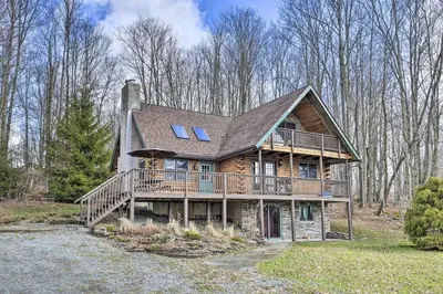 a large wooden house with a large deck at Log Cabin and Suites Close to Elk Mountain Ski Resort in Pleasant Mount