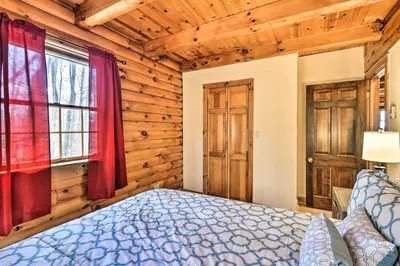 a bedroom with a bed in a room with wooden walls at Wander & Unwind, Log Cabin and Suites Close to Ski Mountain in Pleasant Mount