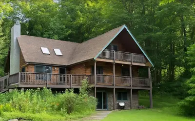 a large wooden house with a large deck at Log Cabin and Cottage Near Elk Mountain Ski Slopes in Pleasant Mount