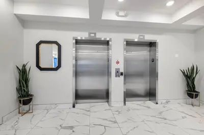 two silver elevators in a lobby with two plants at Stylish Studio - Pool, Gym & Balcony Bliss in Philadelphia