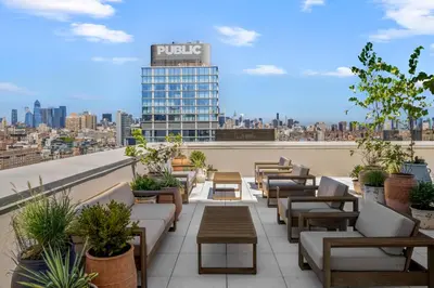 a rooftop patio with couches and tables and a building at Freeman 303 by Rove Travel - 1BR Condo with Shared Amenities in New York