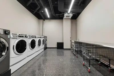 a laundry room with three washing machines in it at Freeman 801 by Rove Travel - Studio with Shared Amenities in New York