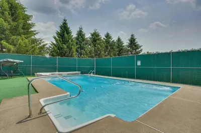 a large swimming pool with a green fence at Country Escape Close to Ski Resort in Pleasant Mount