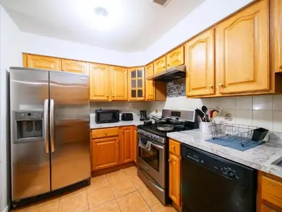 a kitchen with wooden cabinets and a stainless steel refrigerator at Cozy Private Room with Shared Kitchen near NYC in Jersey City
