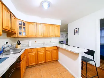 a kitchen with wooden cabinets and a sink at Cozy Private Room with Shared Kitchen near NYC in Jersey City