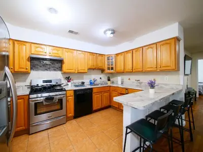 a kitchen with wooden cabinets and a stove top oven at Cozy Private Room with Shared Kitchen near NYC in Jersey City