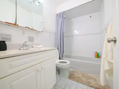 a white bathroom with a toilet and a tub and a sink at Mins to NYC Comfy Private Room in Shared Home in Jersey City