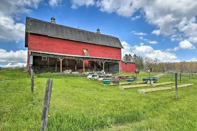 a red barn in a field with a fence at Suite to Unwind Close to Skiing in Pleasant Mount