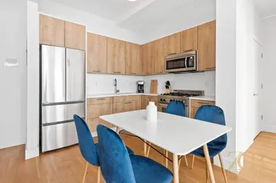 a kitchen with a white table and blue chairs at Gorgeous and Fully Equipped Luxury 1 Bedroom Apt in New York