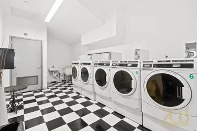 a laundry room with four washing machines on a checkered floor at Newly Renovated 1 Bedroom Apt - Elevator - Laundry in New York