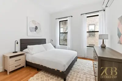 a bedroom with a bed and a desk and windows at 517 -41D Gorgeous and Fully Equipped Luxury 1 Bedroom Apt in New York
