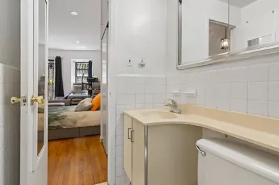 a white bathroom with a sink and a bedroom at Stylish Studio in Central Park in Best Location Ever in New York