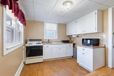 a kitchen with white cabinets and a black appliance at Moonbeam Suite-Private Room in Serenity Manor in Chester