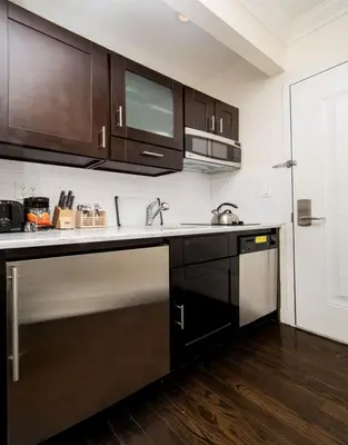 a kitchen with black cabinets and stainless steel appliances at East Village by Vibe I in New York