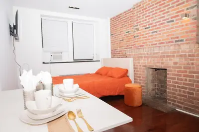 a living room with a table and a brick wall at West47 Village Getaway - Subway & Local Cafés in New York