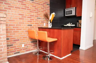 a bar with an orange stool next to a brick wall at West47 Village Getaway - Subway & Local Cafés in New York