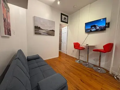 a living room with a couch and a table and a tv at Hudson Crown Suites in New York