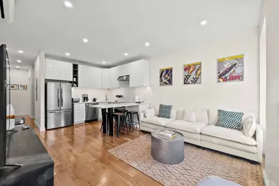 a white living room with a couch and a kitchen at Carroll Place II - Bright 3BR Carroll Gardens Apt in Brooklyn