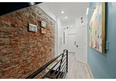 a hallway with a brick wall and a white door at Center City Philadelphia GSN Bloom 1 in Philadelphia