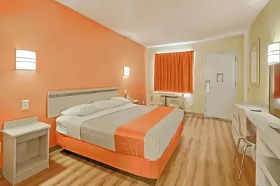 a bedroom with a large bed with an orange wall at Red Carpet Inn And Suites in Maple Shade